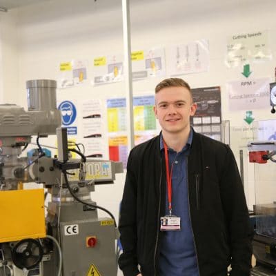Chris stands in an engineering classroom