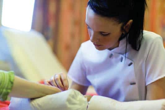 Beautician manicures a customer's fingernails.