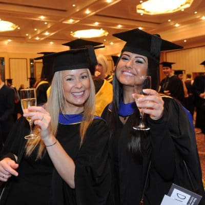 graduates holding glasses at graduation