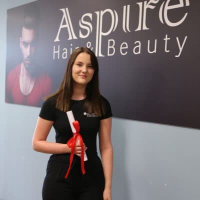 Hair & beauty student stood in front of Aspire sign