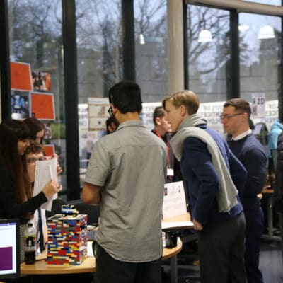 Students standing at stalls at a fair