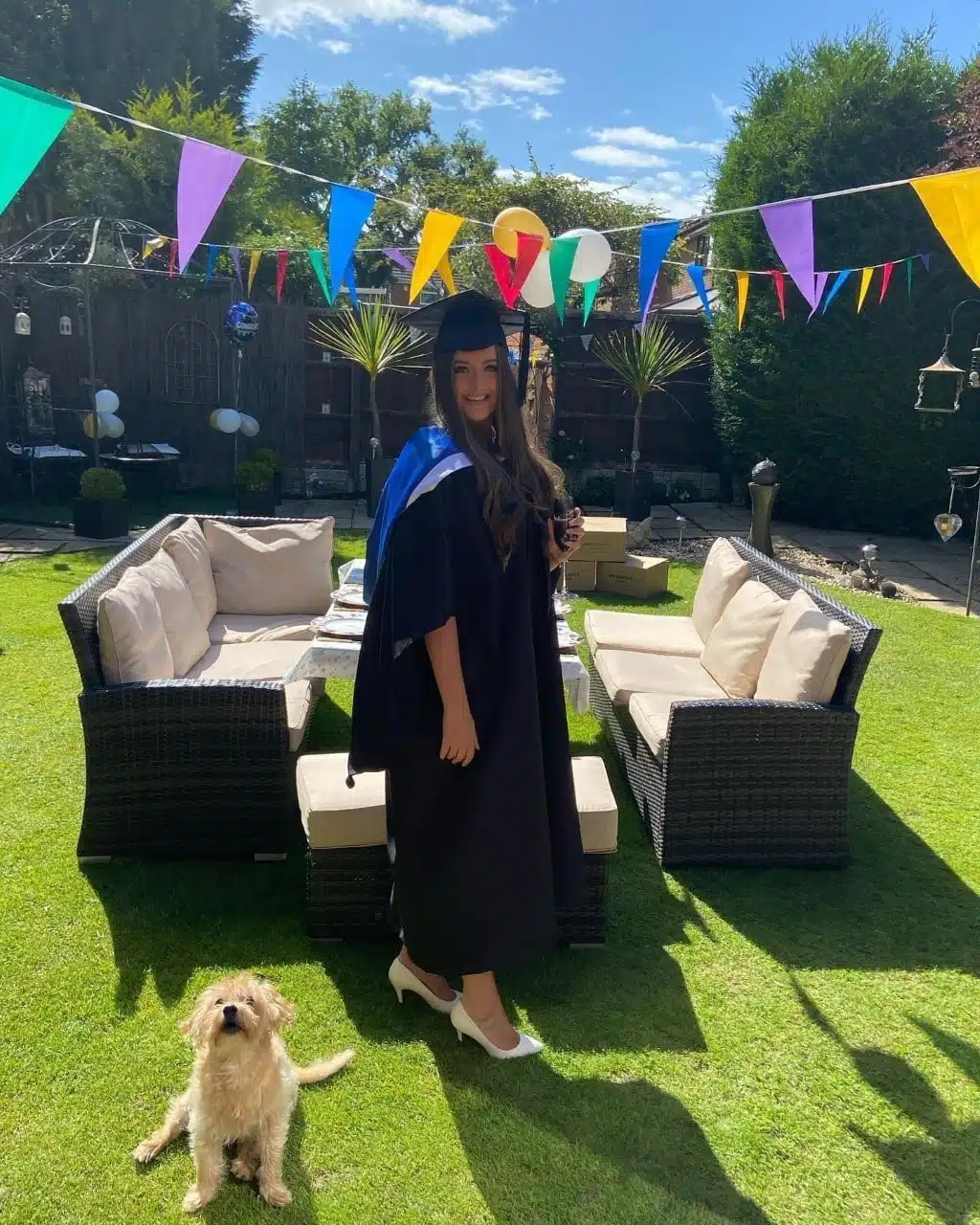 Lauren stands in her garden in a graduation gown.