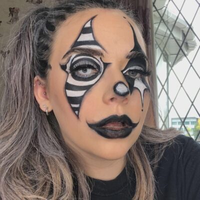 a female student has a clown style pattern around both eyes and black lips