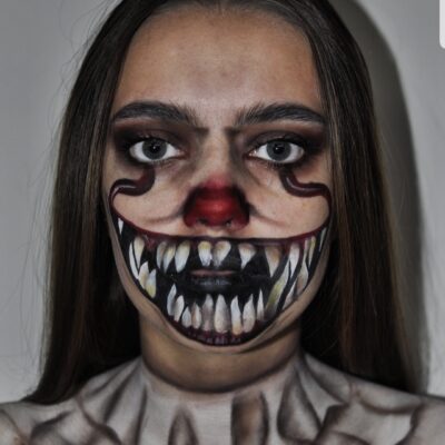 A student has a painted fanged mouth painted over the lower part of her face