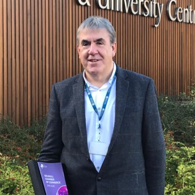 Mick Westman stands receiving the award outside the college with the award.