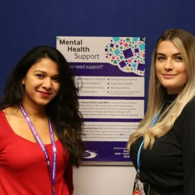Fathima and Blair stand in front of a Mental Health Poster