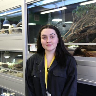 Angel Pooler stands in front of lizard tanks at the College in the animal department