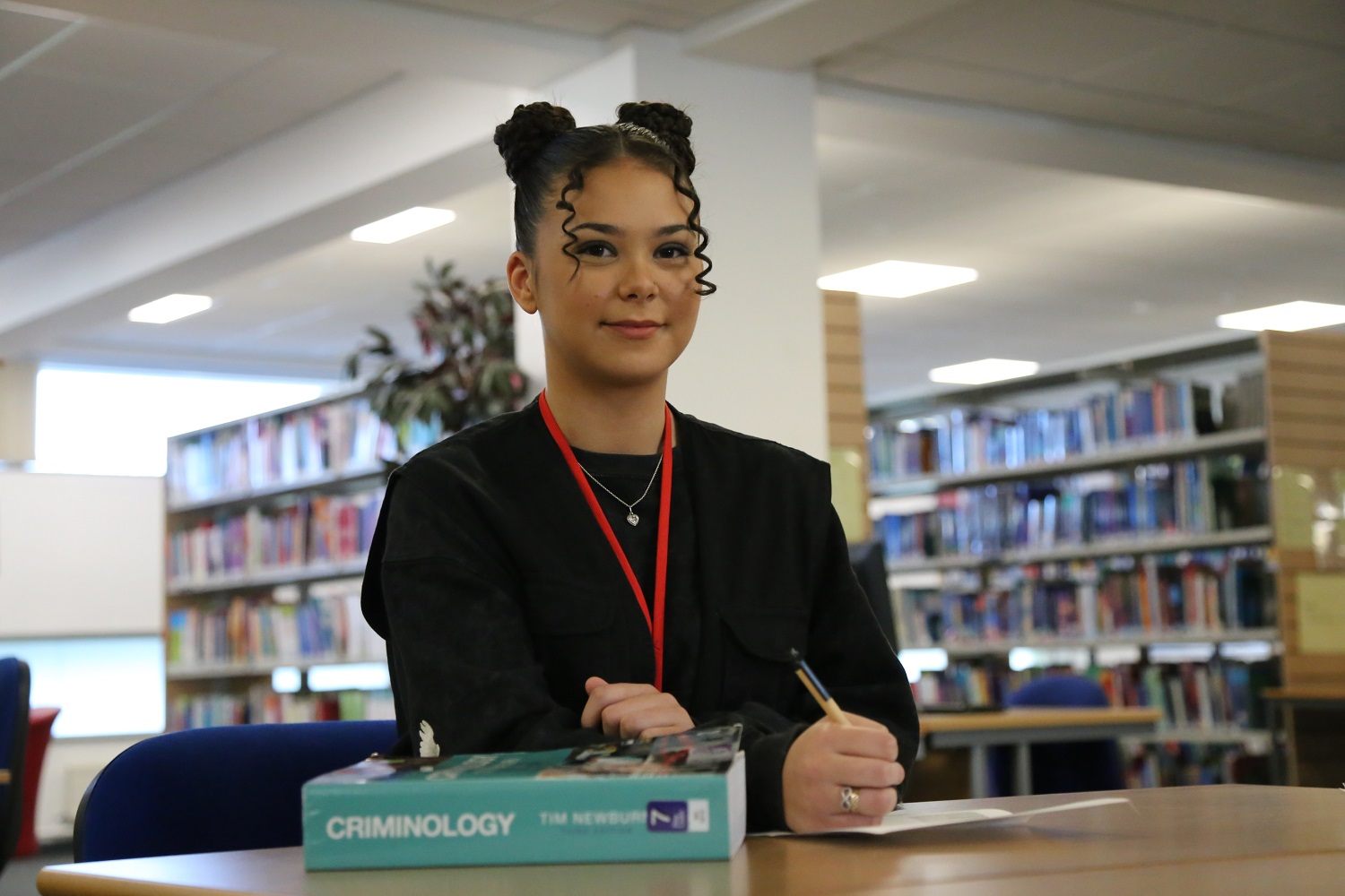 Nicole working in the library with a criminology textbook at her side on the desk