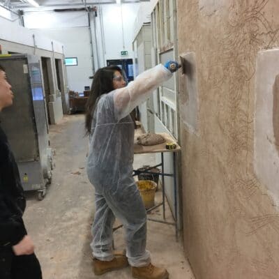 Rachel Arnold plastering a wall in the workshop.