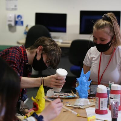 2 students, a male and female, work in a pair to paint models