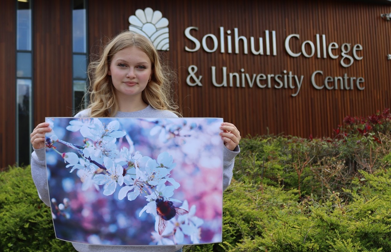 Hattie holding her winning bee image print outside of college.