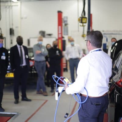 Alan stand in a workshop discussing with attendees about the vehicle