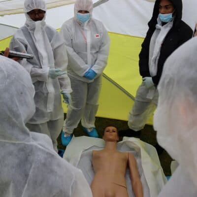 students stand around the mannequin in the tent