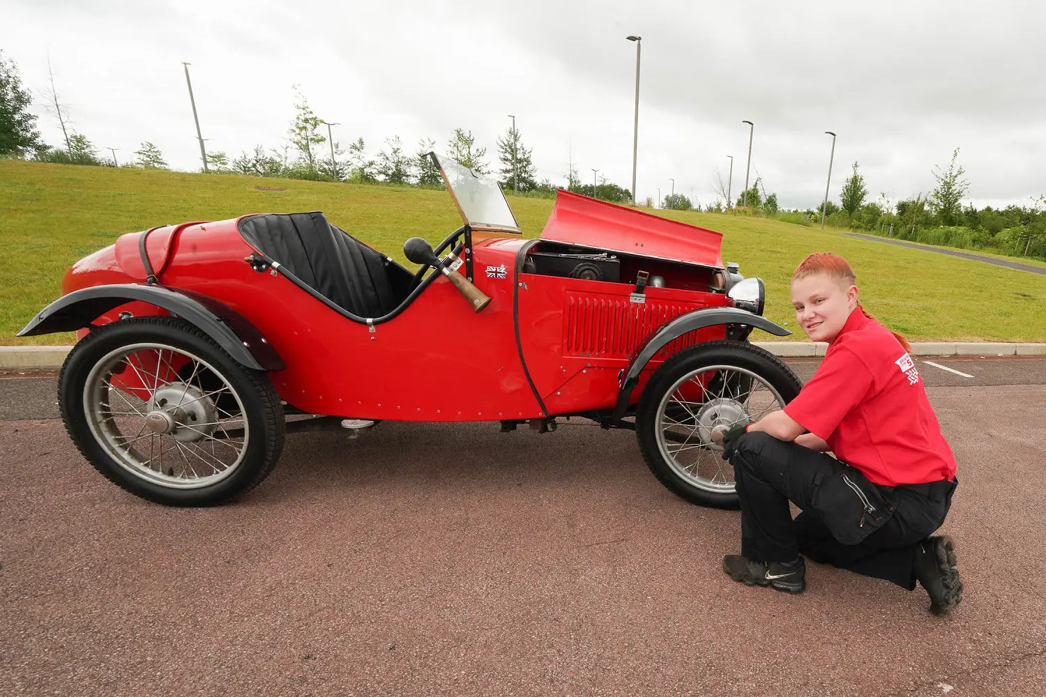 Tianna kneels near a wheel of an old classic car