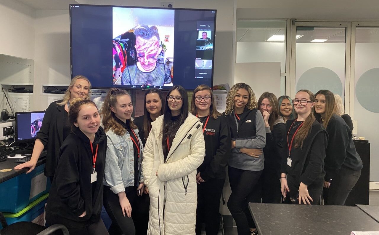 Make up students in front of a big screen with James Mac