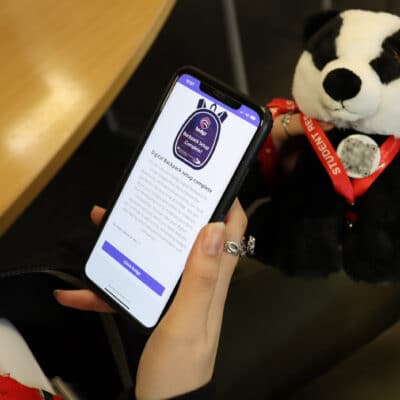 student holding phone and badger plush toy