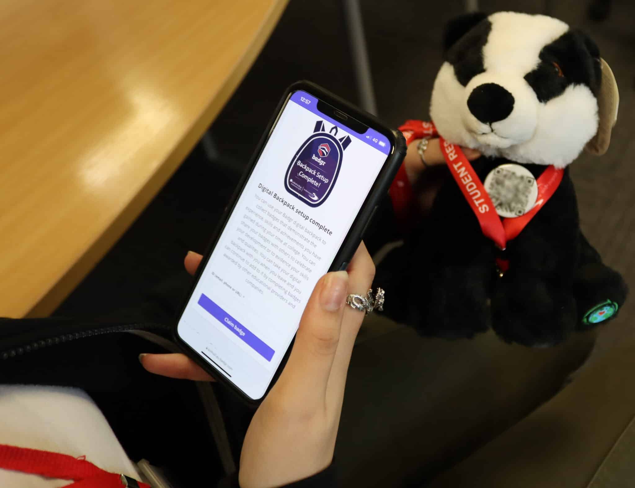 student holding phone and badger plush toy
