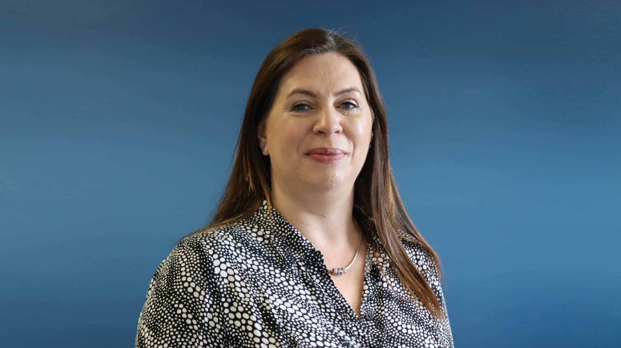 Blue Background, Rebecca standing wearing a black and white patterened top