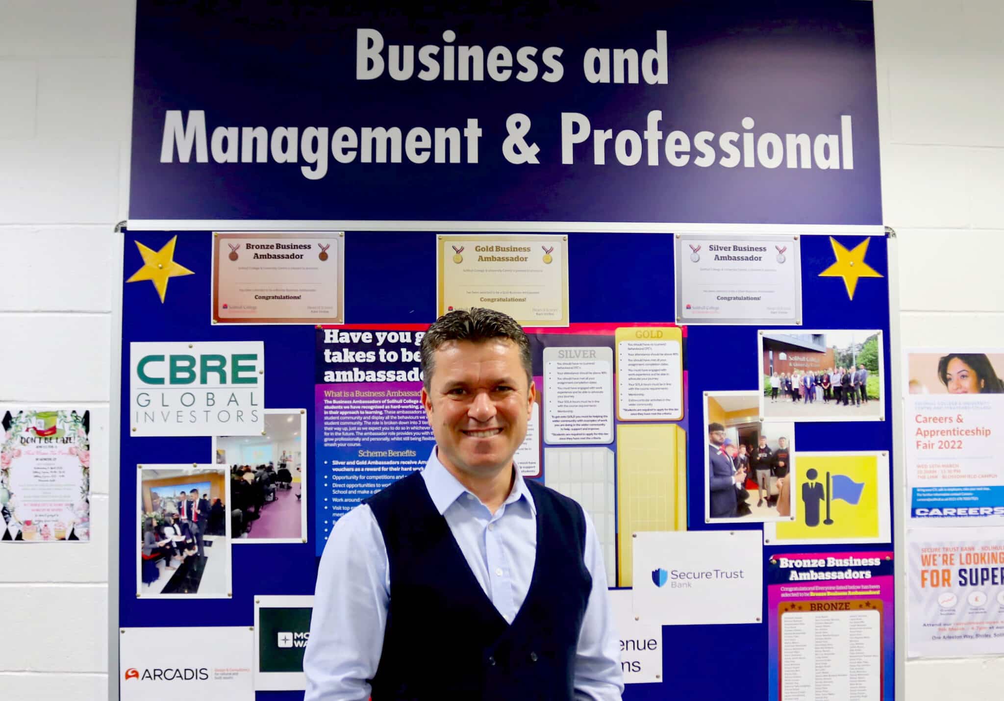 Hakan standing in front of board that reads Business and Management & Professional at the top