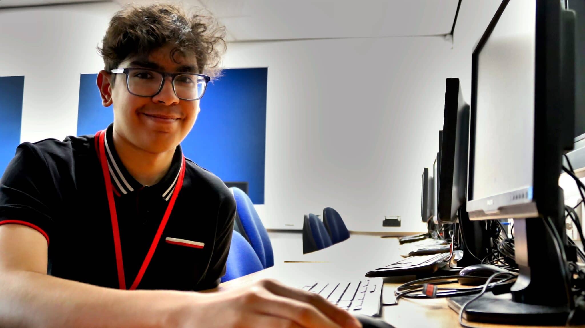 student wearing glasses sat in front of computer