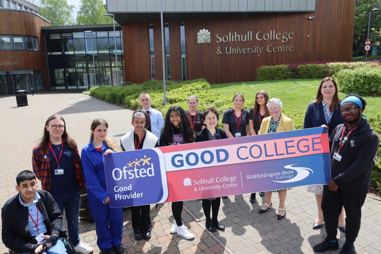 Students and three staff members standing in front of College campus with Ofsted 'Good' Banner