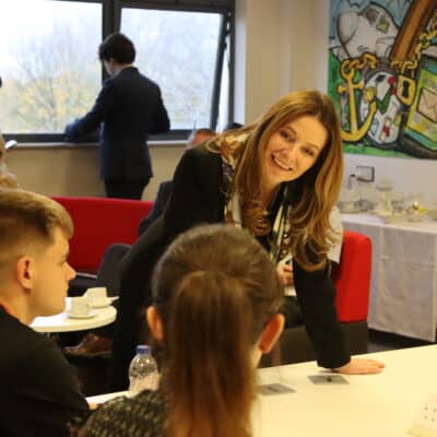 MP leans on table and talks to two students