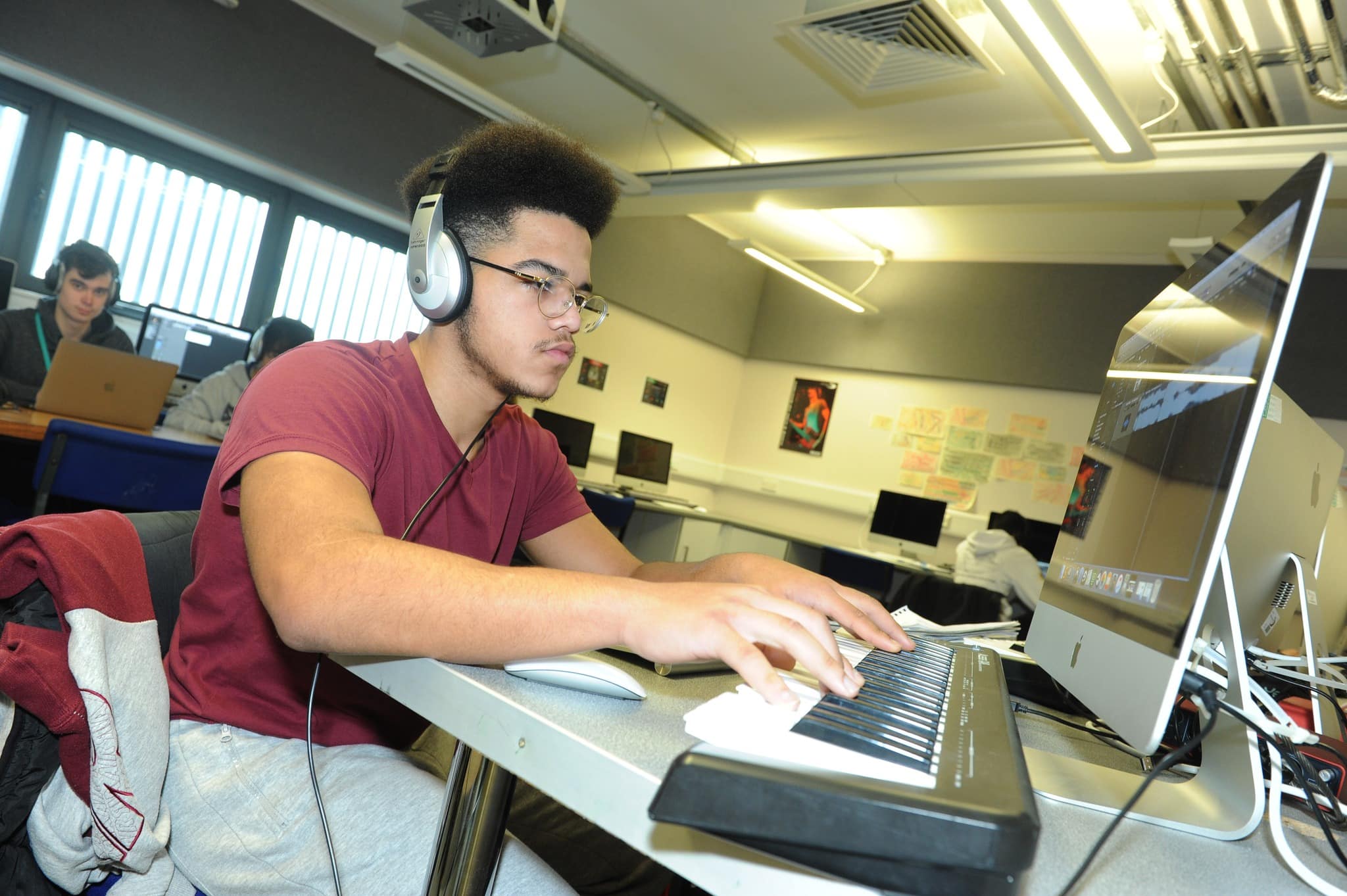 student playing keyboard with headphones on
