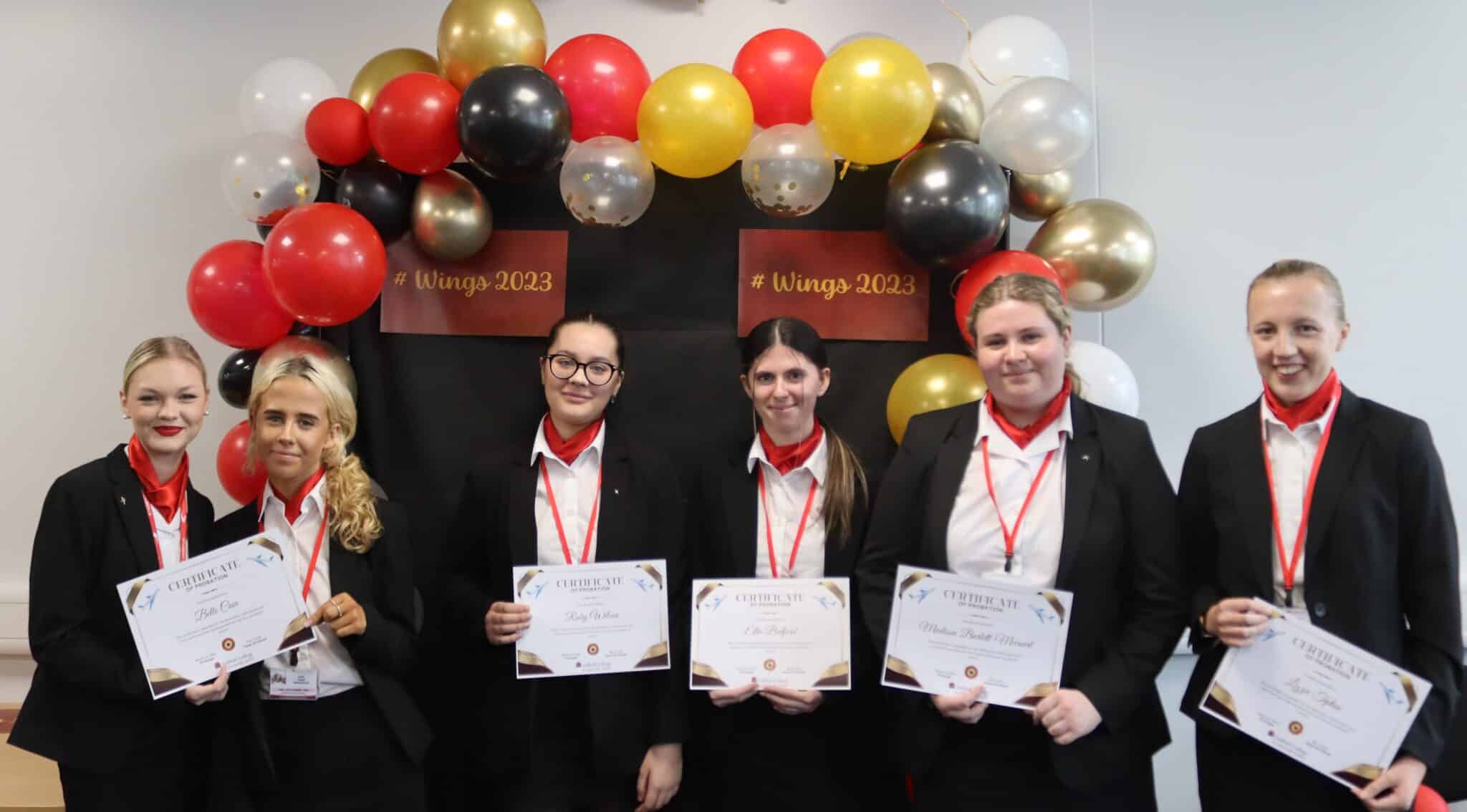 students standing in front of balloons with their certificates