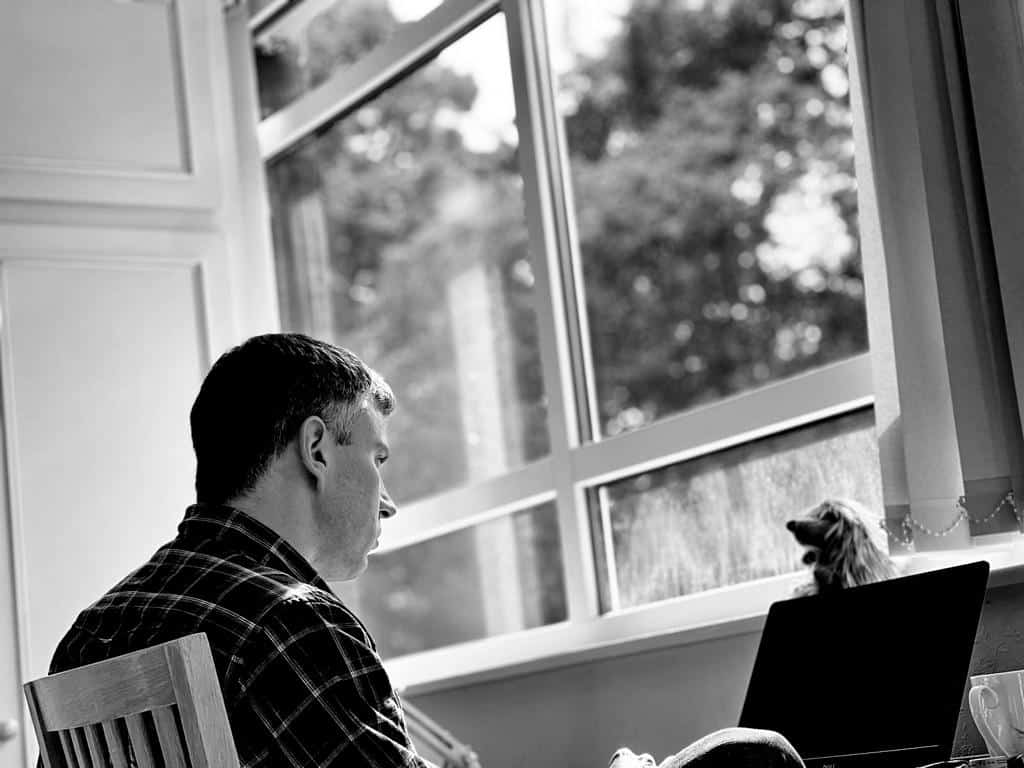 Richard sitting at his computer in front of a window
