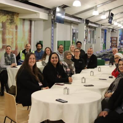 A photo of staff sat around tables looking at camera
