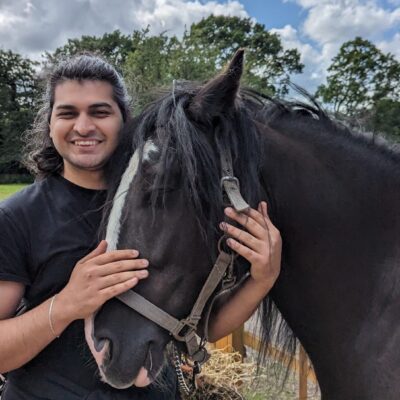 student stood next to horse with hands around its head