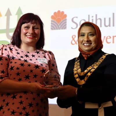Yvette and the Mayor of Solihull stand in front of powerpoint with award
