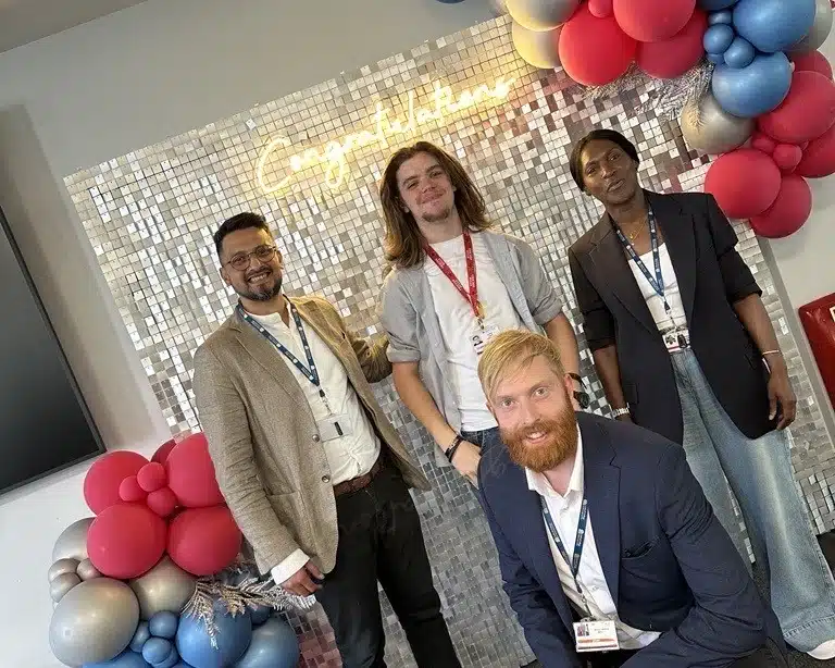 patrick standing in front of celebration decoration with 3 teachers