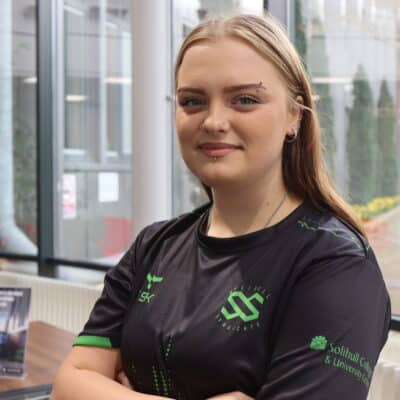student wearing esport jersey crossing arms and looking at camera