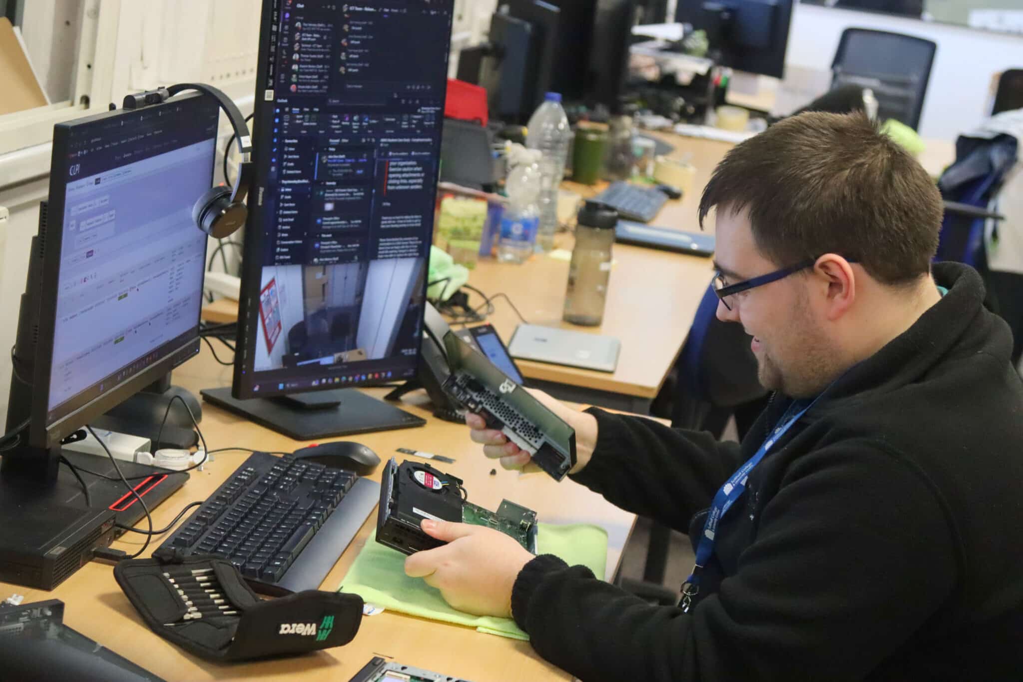 Troy working on a hard drive in his office with computers around
