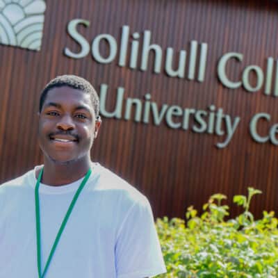 Tami standing in front of college logo