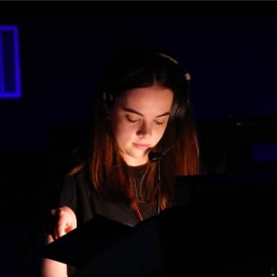 Eden with headphones on, working on set