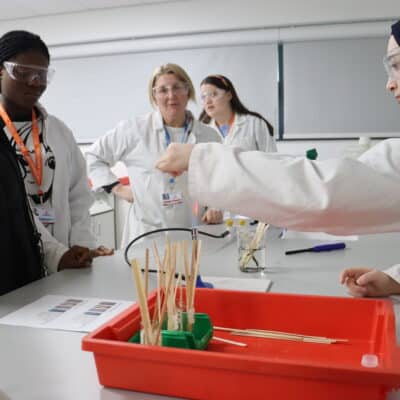 A group of students in a science lab wearing goggles doing a science experiment