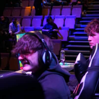 students sat at a compute, in a purlple lighting playing esports games