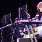 Students sat an a computer with headphones on playing on it