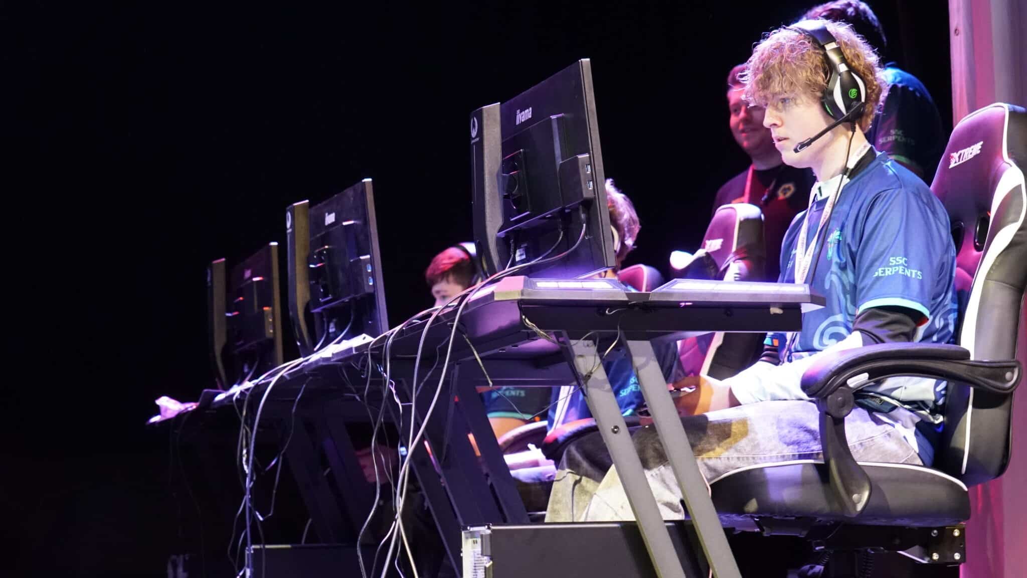 Students sat an a computer with headphones on playing on it