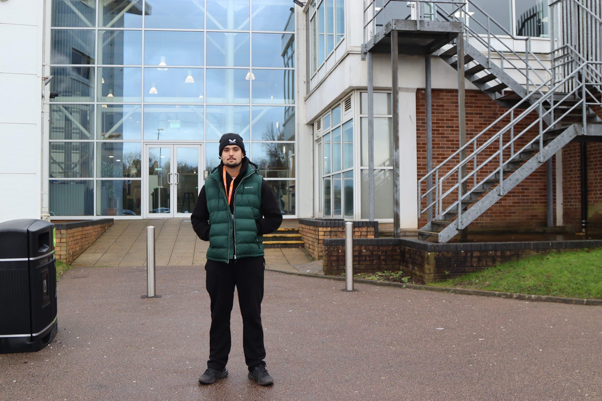 Student stood outside a sports centre in a green coat