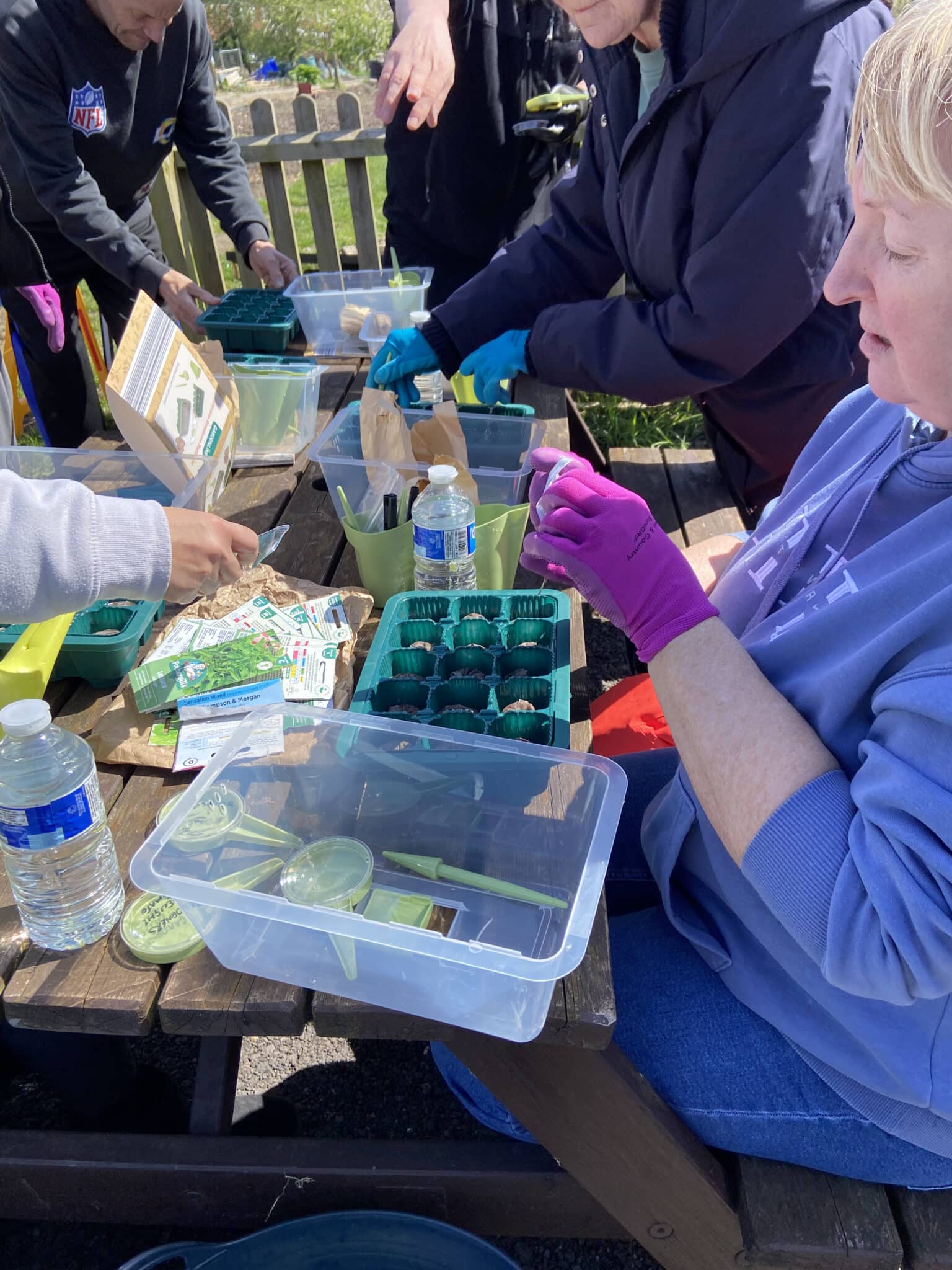 lady sowing some seeds sat on a table at the community garden