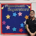 Shoaib standing in front of a sign saying 'Placement Superstars'
