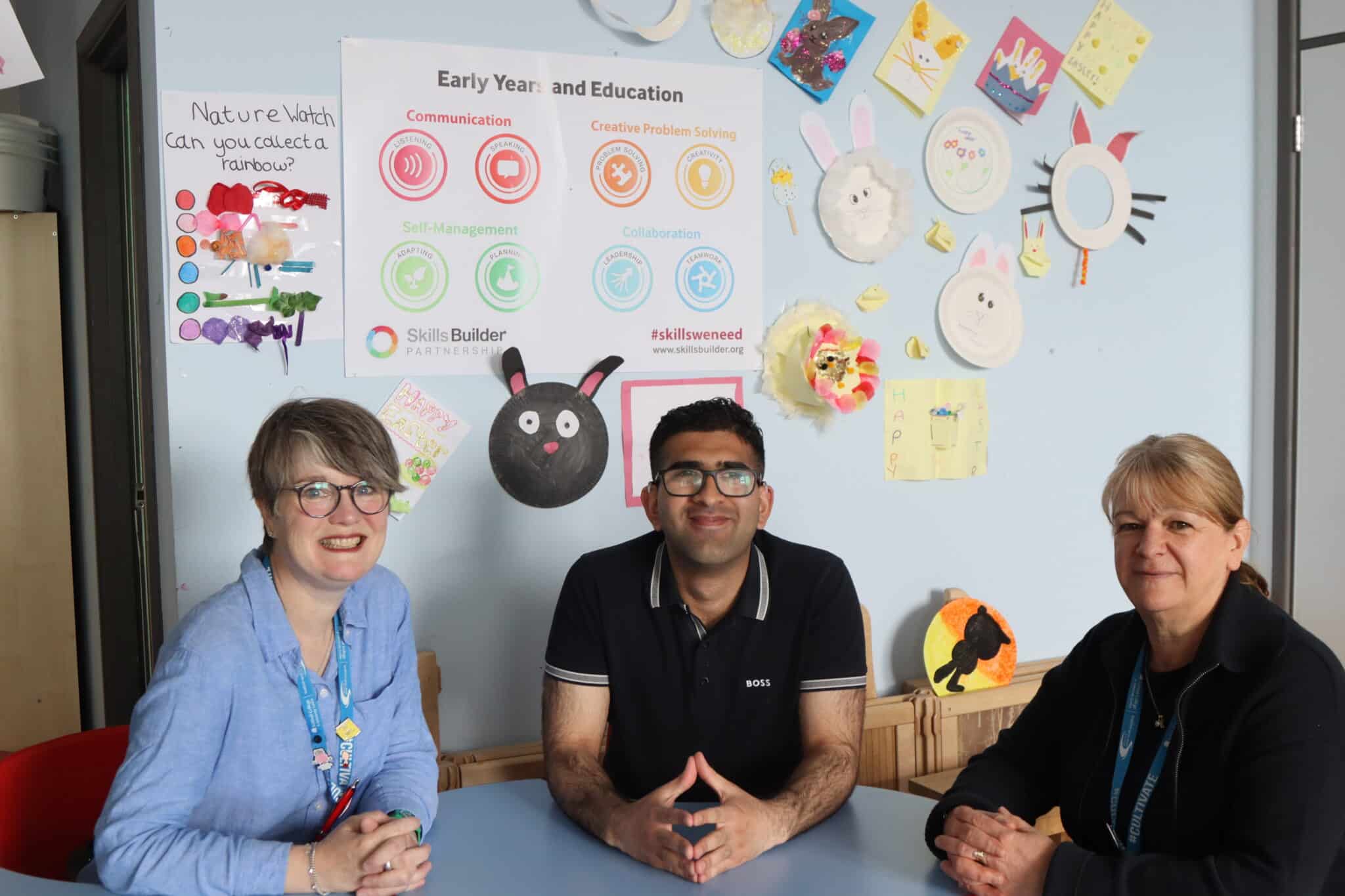 Shoaib with Claire and christine Mason who is Shoaib's support worker sitting at a table in an early years classroom