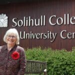 A woman with white blonde hair standing in front of the Solihull College & University Centre sign.