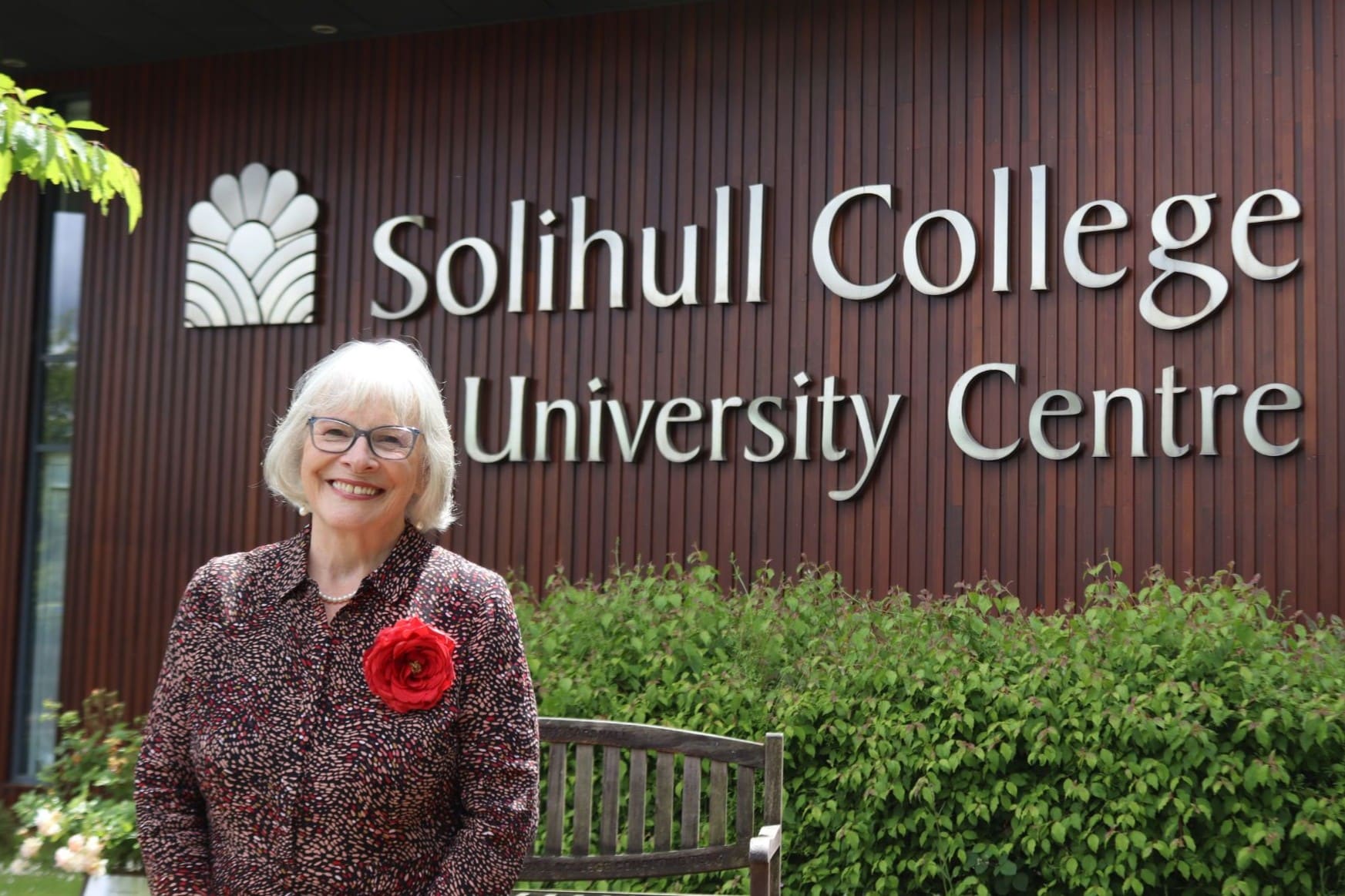 A woman with white blonde hair standing in front of the Solihull College & University Centre sign.