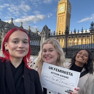 3 adult women stood outside parliament with Big Ben in the background.