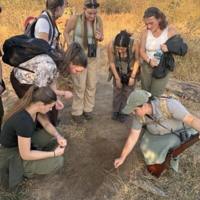 students looking at the ground with someone from the game reserve
